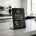 Stand NFC Recensioni Google nero su banco con sfondo luminoso